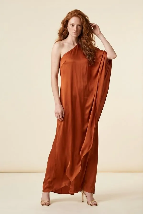 Modelo pelirroja con un vestido de seda color óxido de un hombro en una sesión editorial